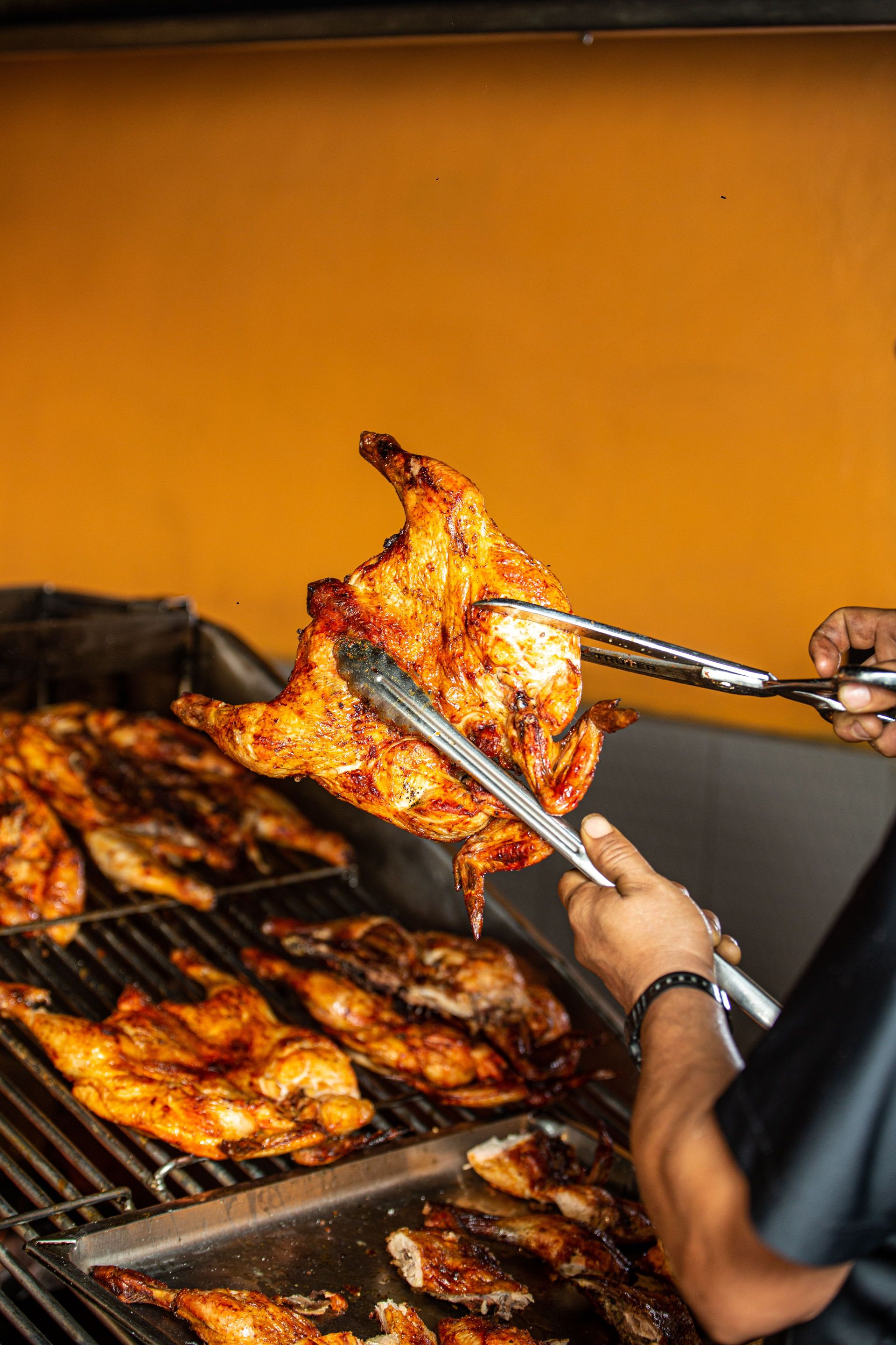Juicy grilled chicken on BBQ grill with tongs, perfect for summer cookouts.